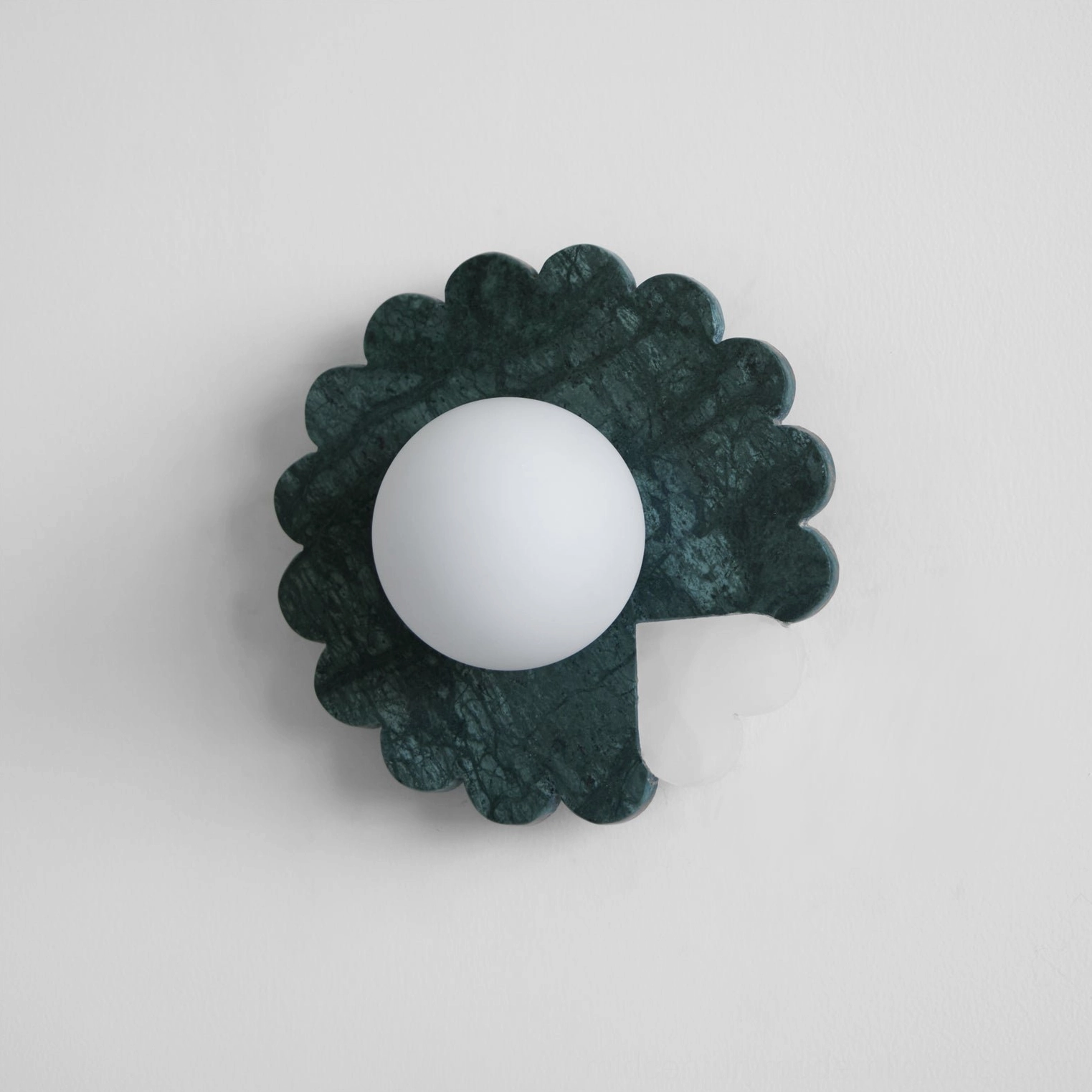 Dark green marble wall sconce with decorative petal silhouette and contemporary design