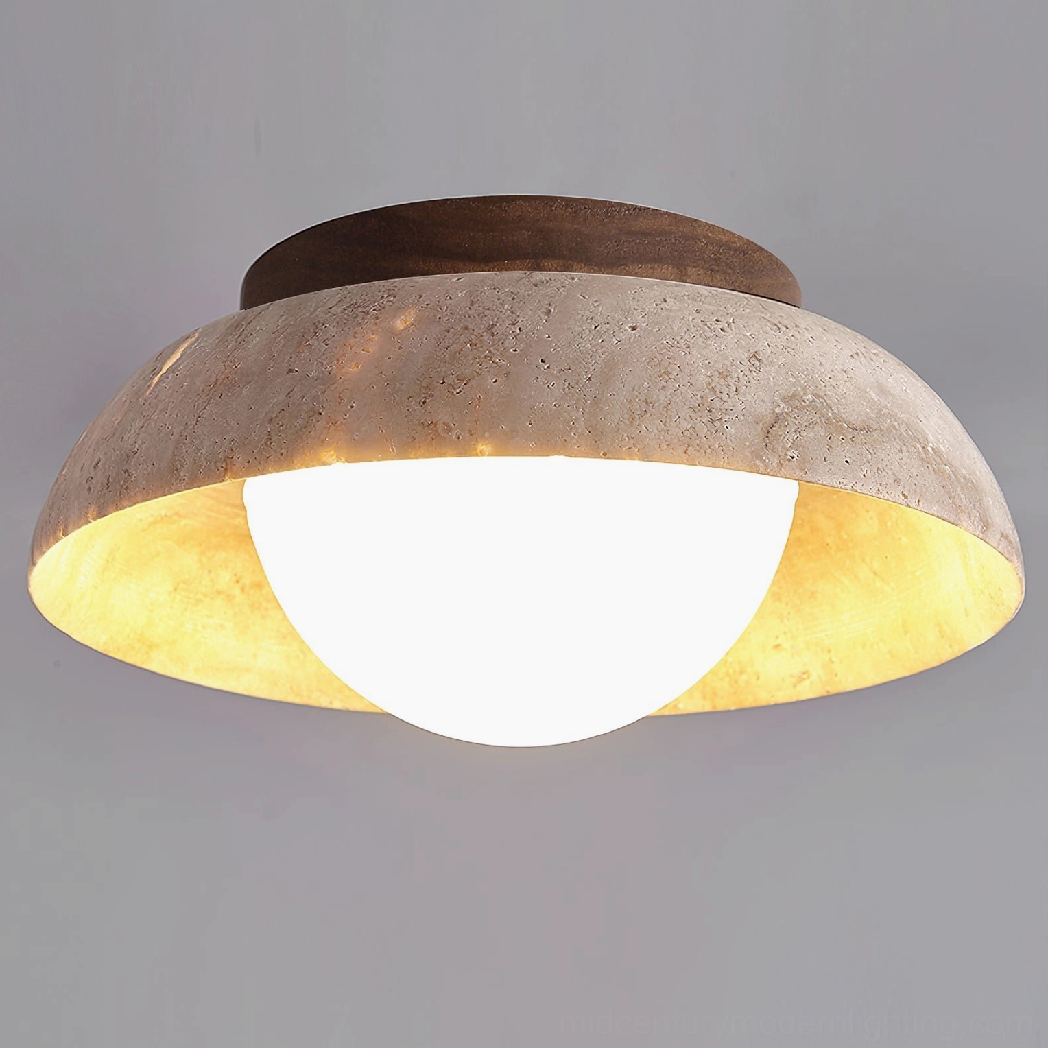 Low-angle front view of Piedra travertine ceiling light showing wide dome shade and bright spherical LED bulb