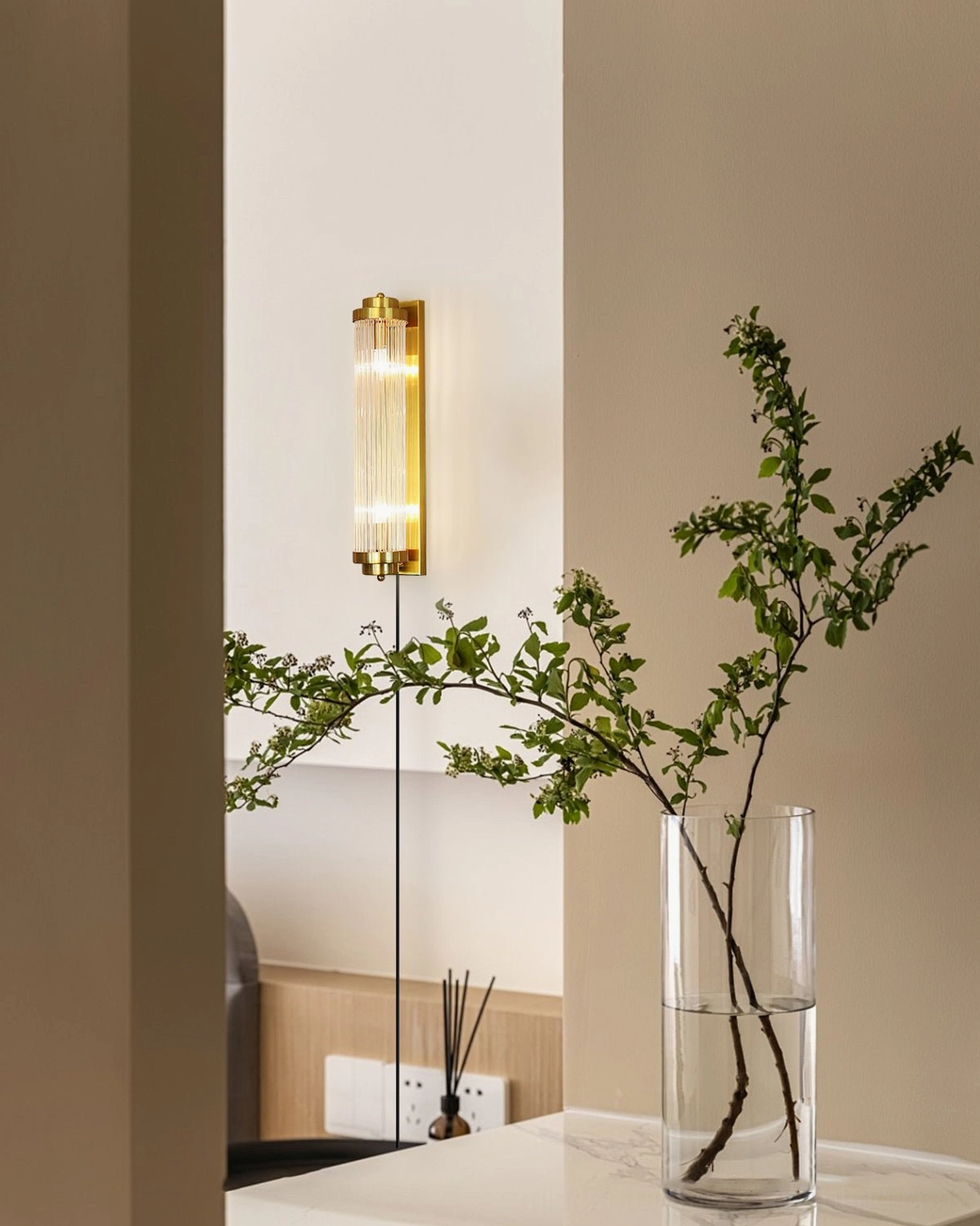 Modern minimalist home entryway with designer wall lamp, showcasing consistent brass and glass construction