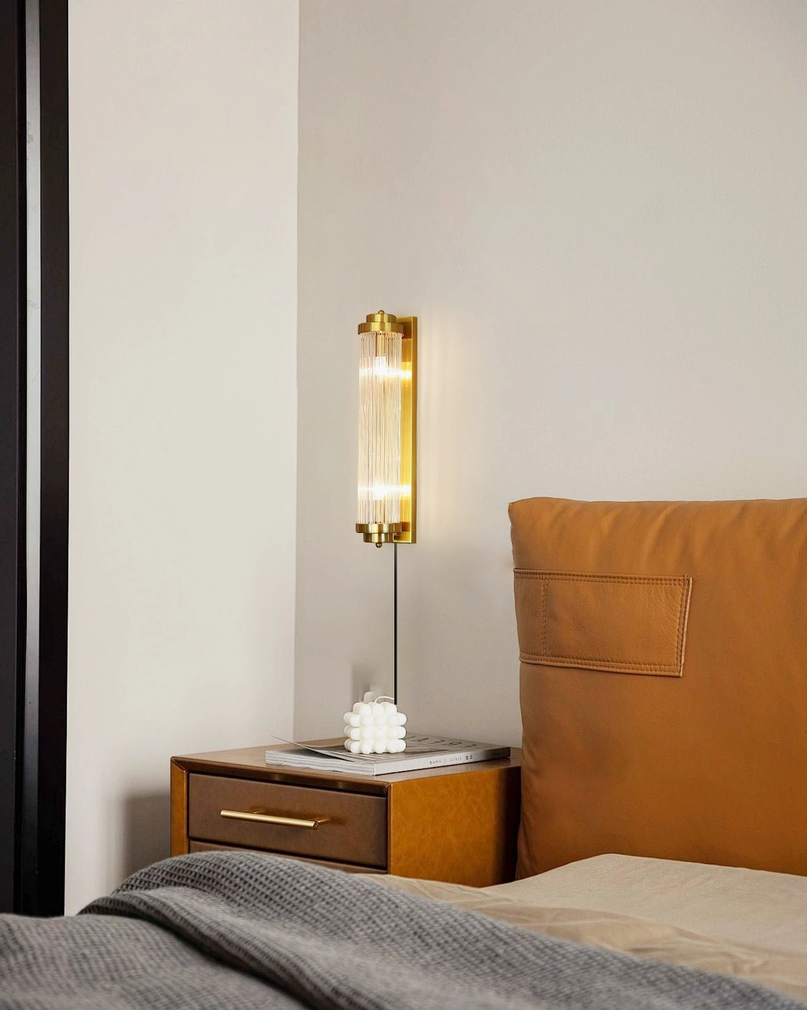 Luxury mid-century wall sconce mounted in warm-toned bedroom with nightstand, creating ambient mood lighting