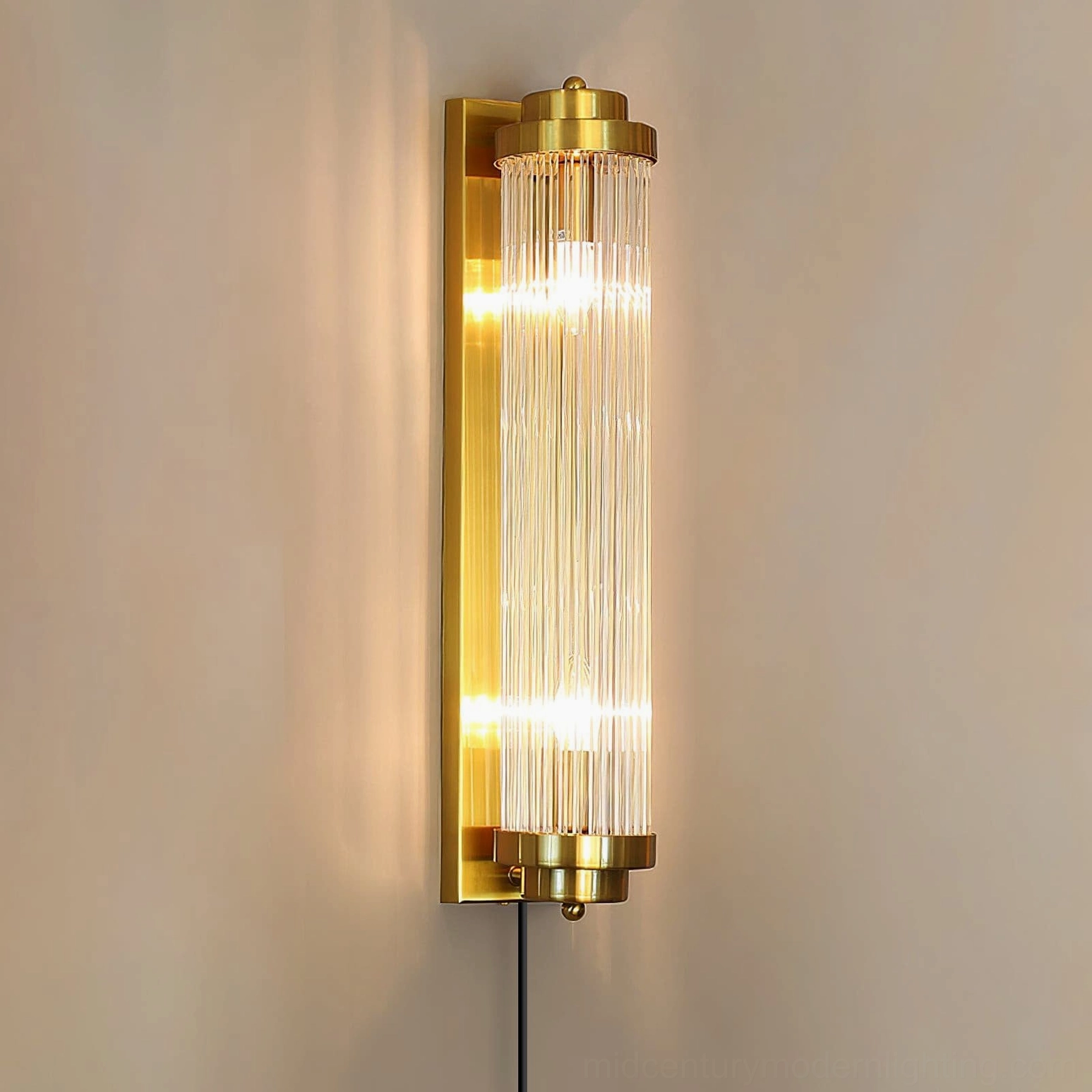 Tall mid-century modern wall sconce illuminated with warm ambient light, side detail showing exposed cord and plug