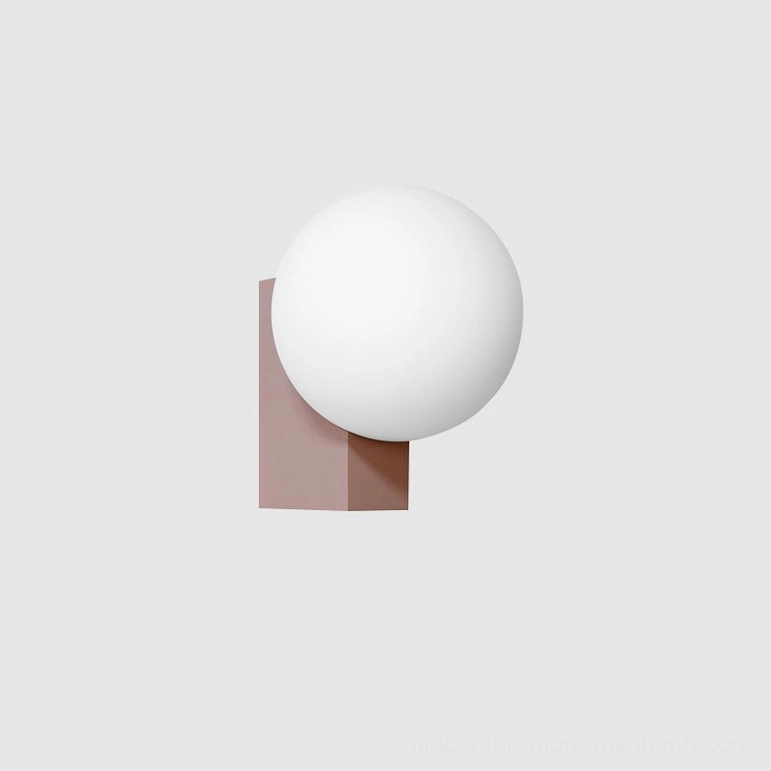 Modern geometric wall lamp in soft pink finish with frosted glass sphere creating contemporary design accent