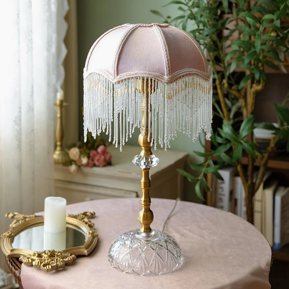 Light pink velvet shade table lamp with beaded tassel trim on bedroom side table