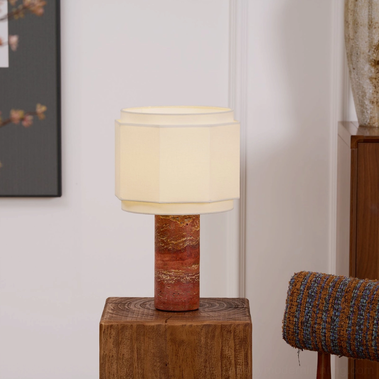 Pipito mid-century modern lamp displayed on wooden pedestal with framed wall art in background