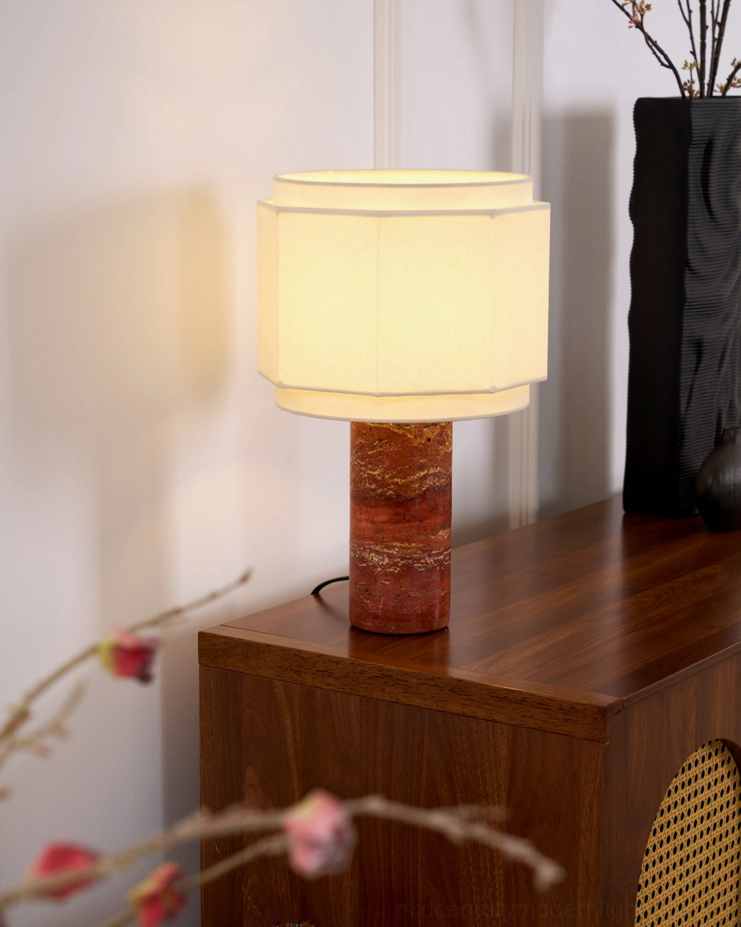 Pipito table lamp providing warm ambient lighting beside black decorative vase on wooden dresser