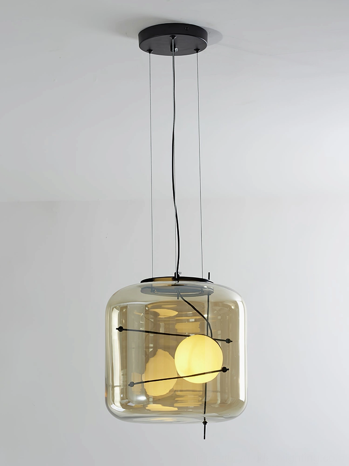 Amber glass Plot pendant lamp front overhead view with dual warm bulbs on white studio background