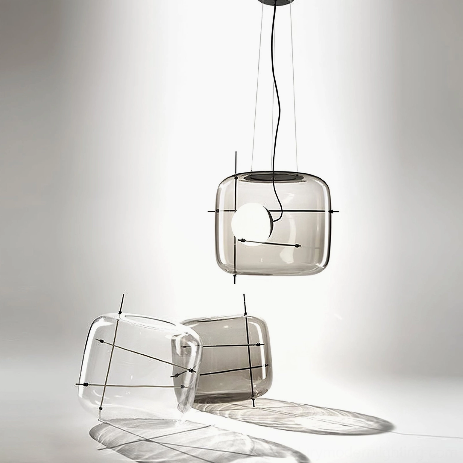 Plot pendant lamp glass shades in clear and smoked finishes with black metal frame and spare parts display