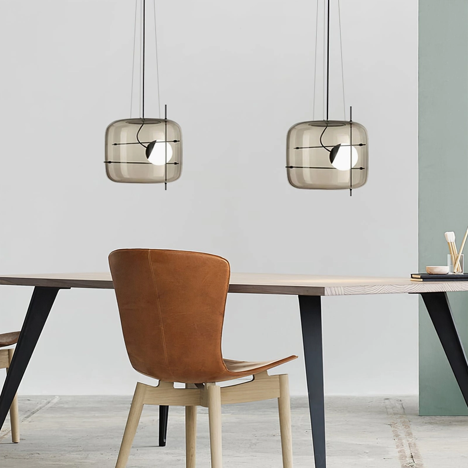 Pair of smoked grey Plot pendant lamps above modern home office desk with matching black fixtures
