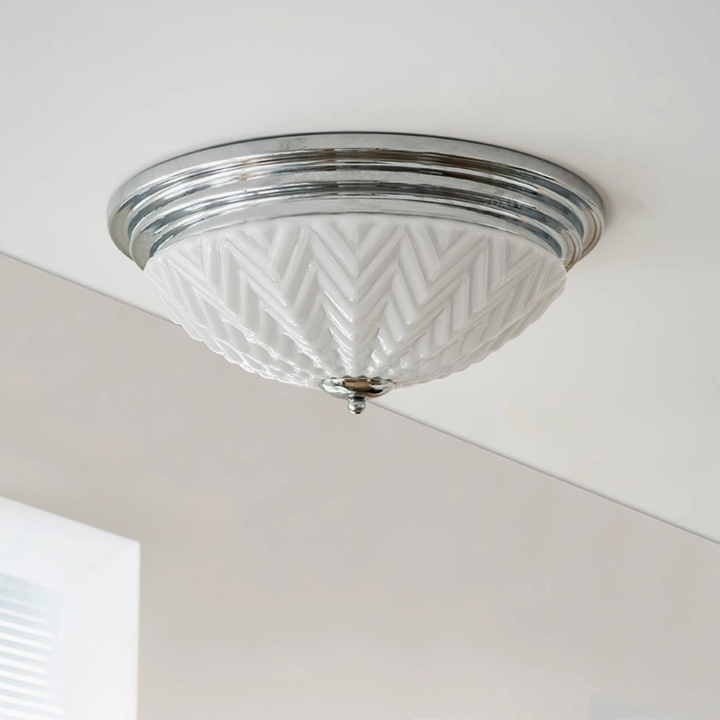 Polished chrome trim ceiling lamp with white frosted glass, modern minimalist aesthetic, studio lighting detail