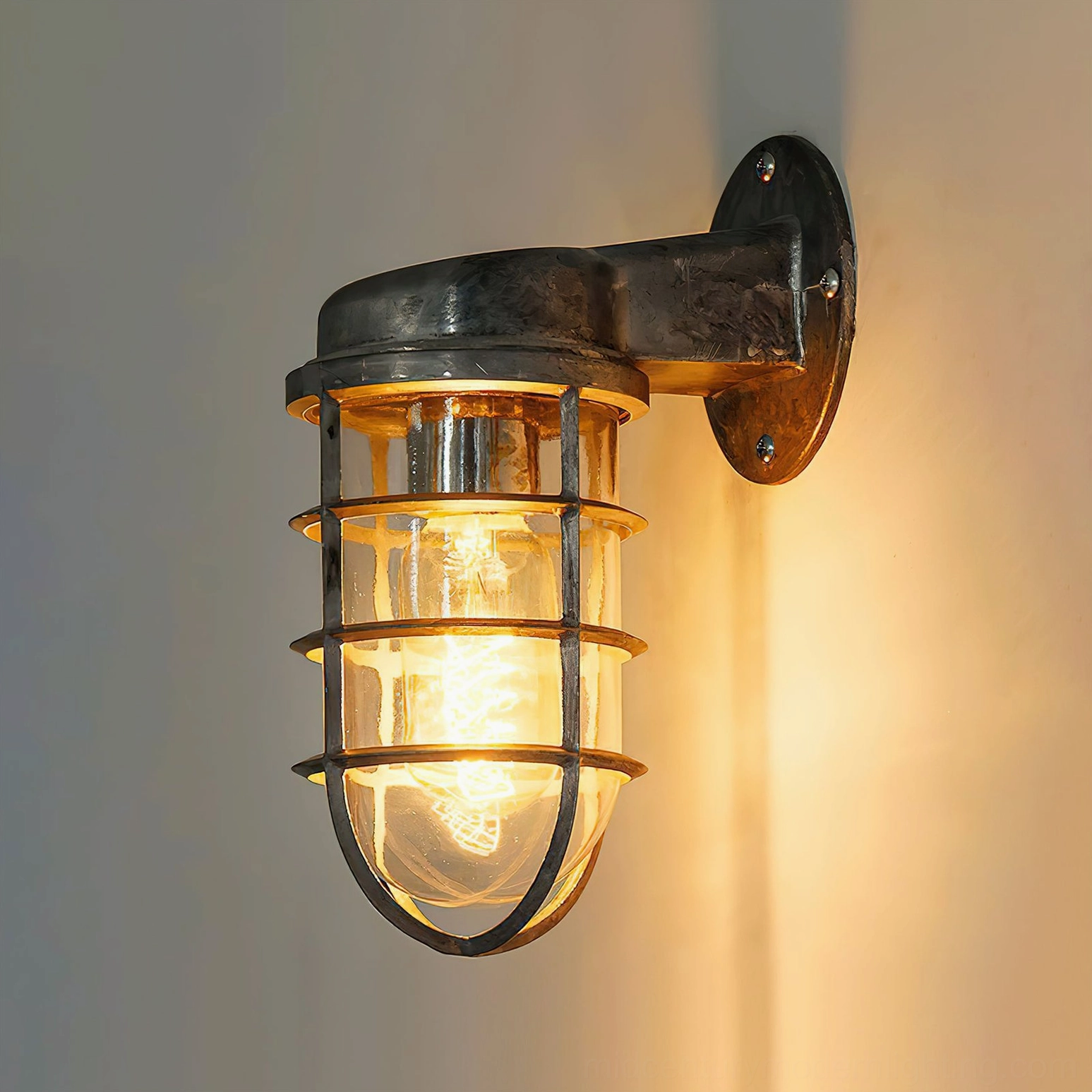 Matte black industrial nautical wall sconce cage lamp close-up on smooth gray wall