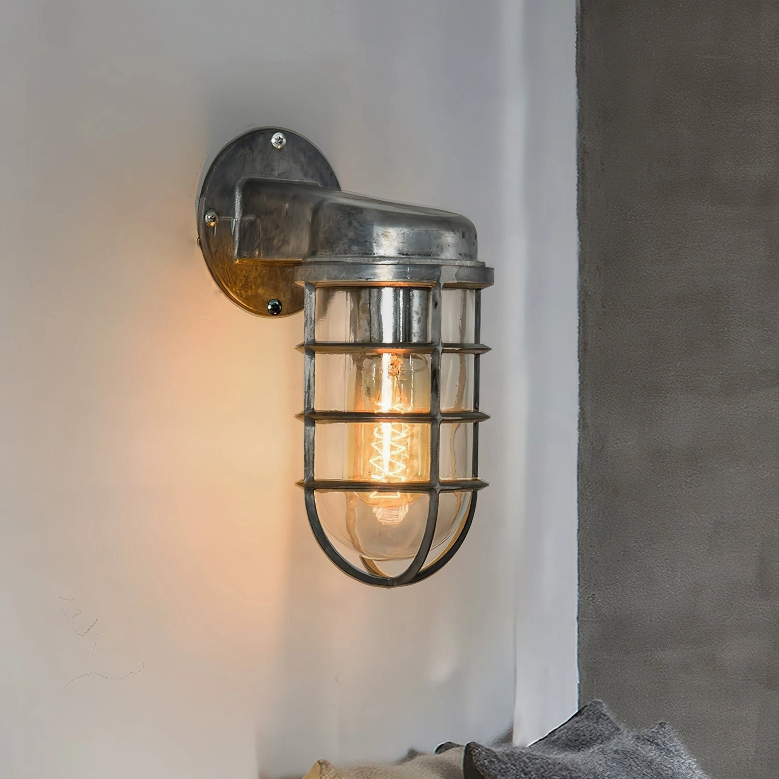 Distressed silver maritime wall lamp mounted on residential gray wall showing aged industrial finish detail