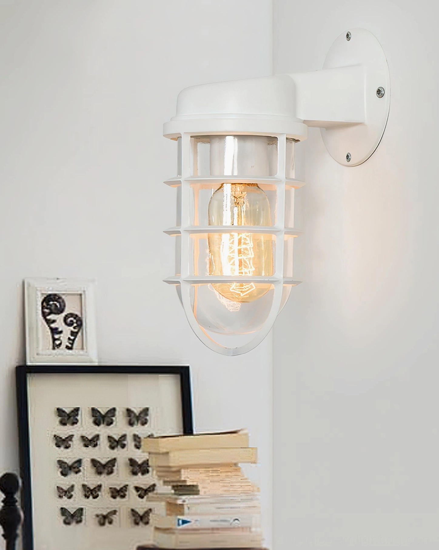 White painted industrial cage wall sconce mounted on home wall with decorative artwork styling