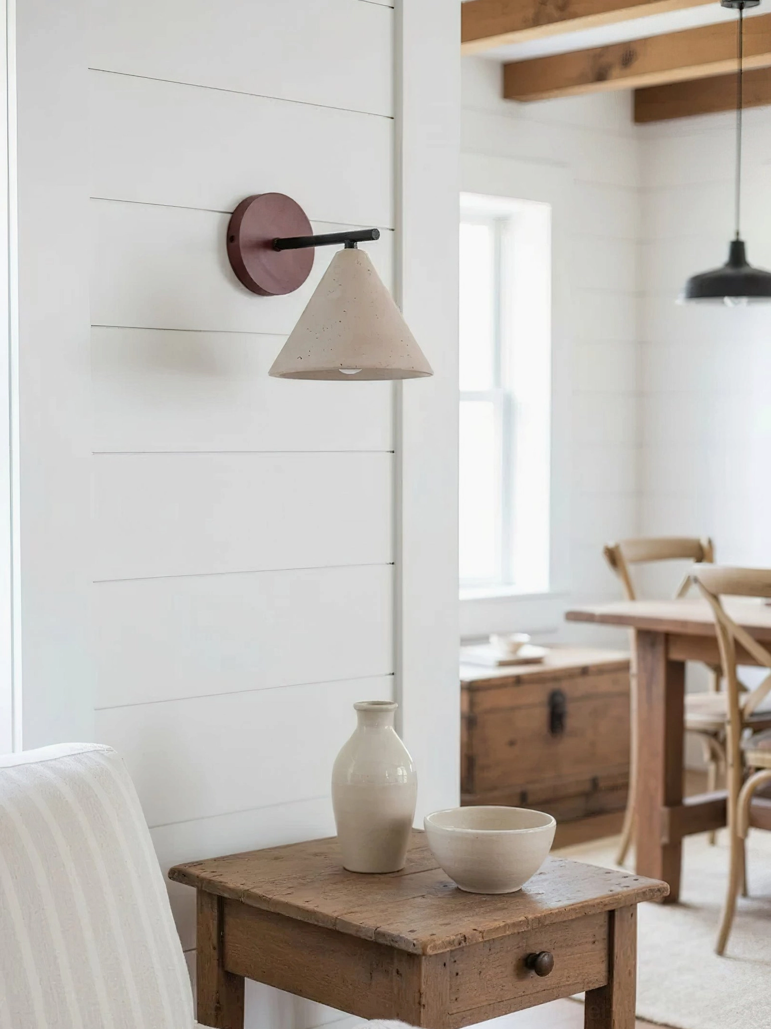 Possio travertine wall light installed in farmhouse dining room, showing modern rustic integration with neutral interior
