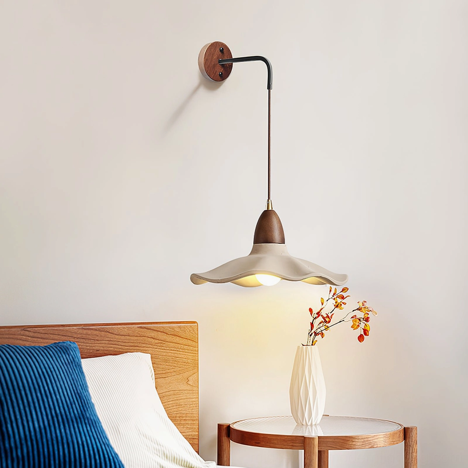 Radha concrete wall lamp installed bedside in cozy bedroom setting with warm minimalist decor