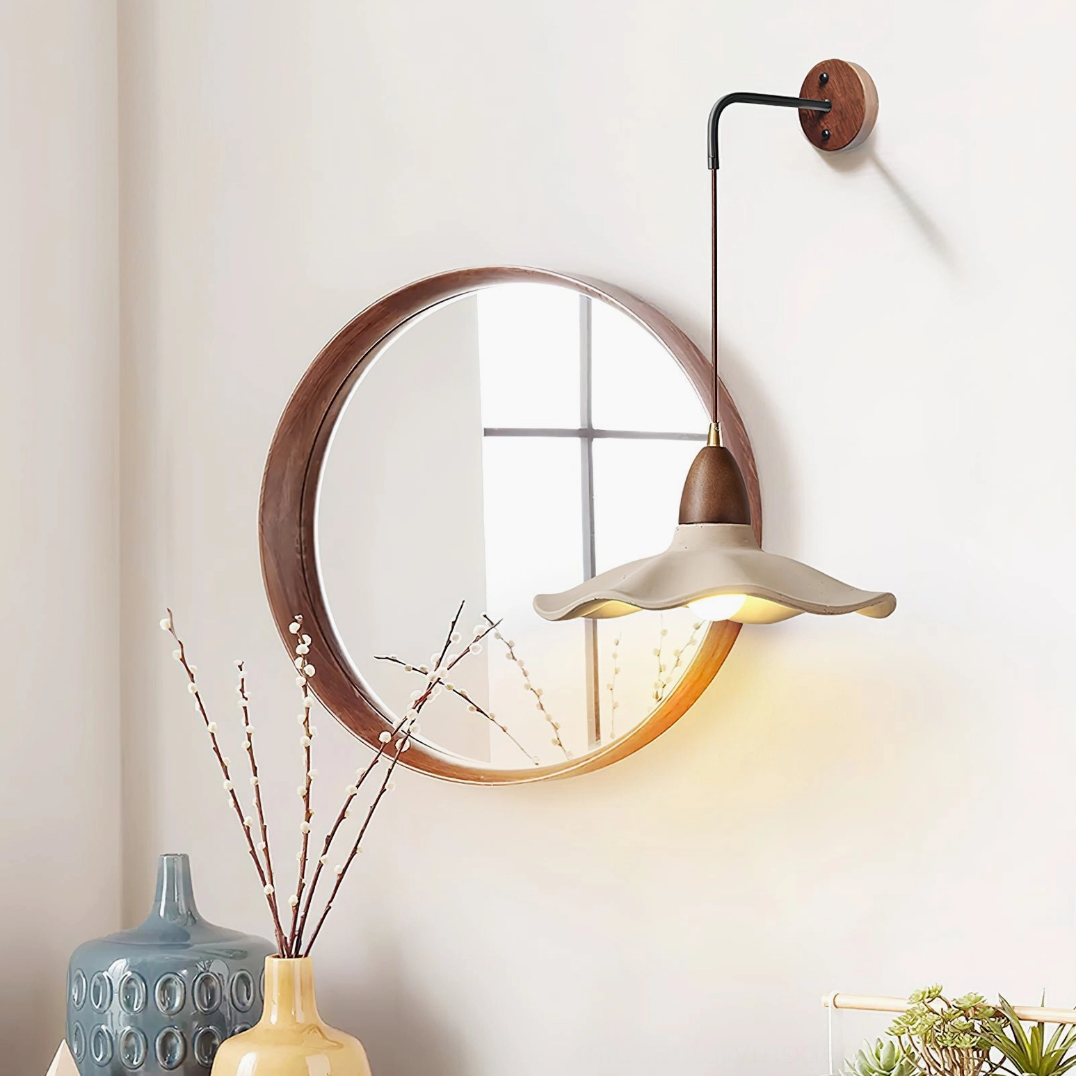Radha sculptural wall lamp side view in entryway setting with wooden mirror and warm neutral decor