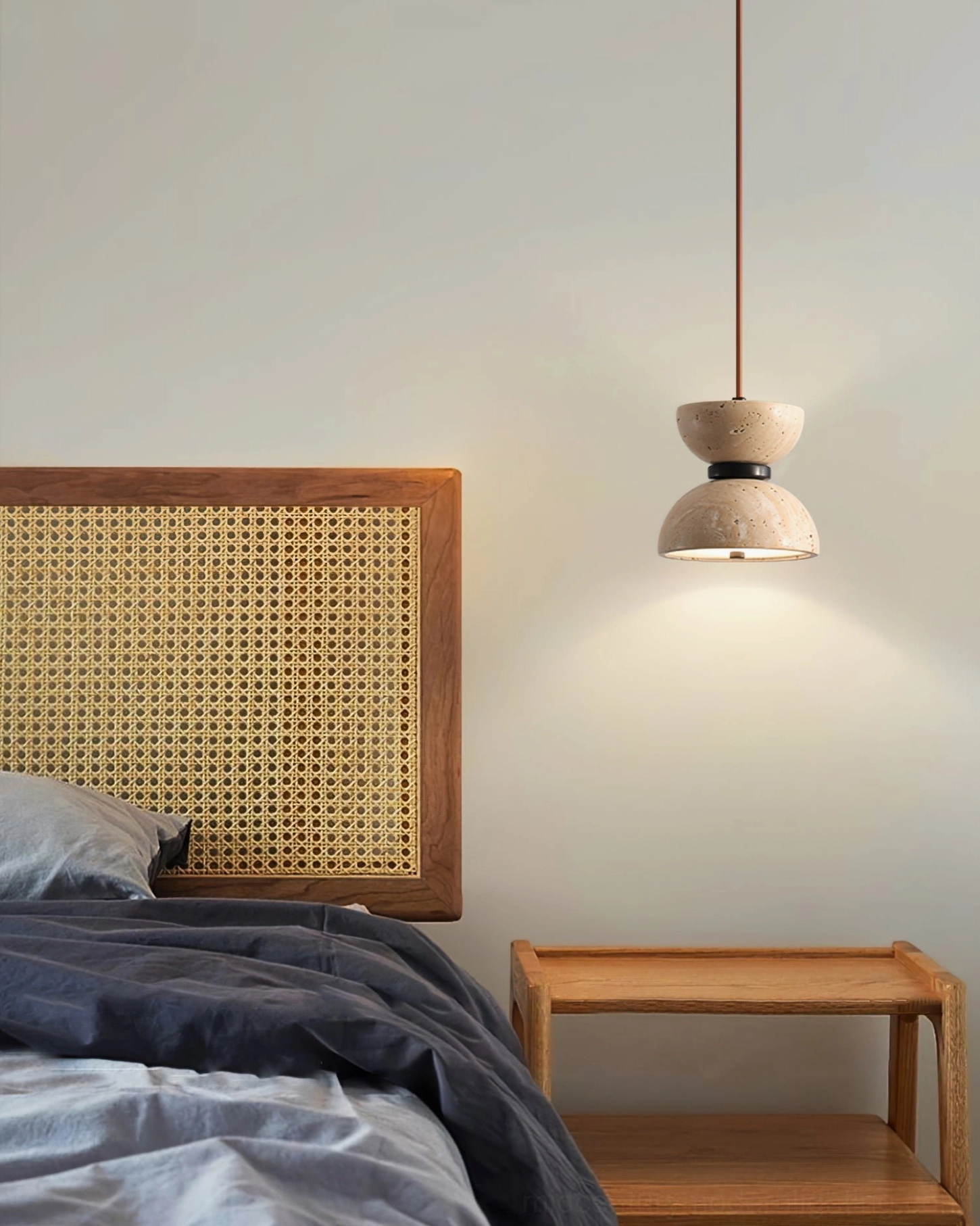 Randolf pendant lamp hanging in modern minimalist bedroom with rattan headboard and warm tonal color scheme
