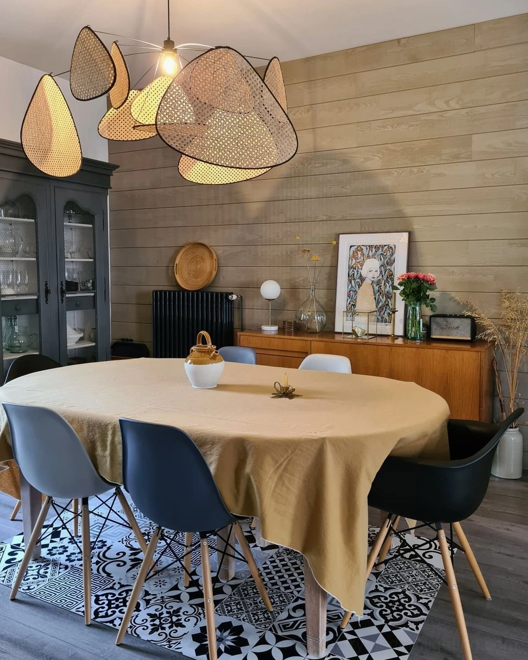 Rattan pendant light above formal dining room table with wooden accent wall, asymmetrical shade arrangement, coordinated decor