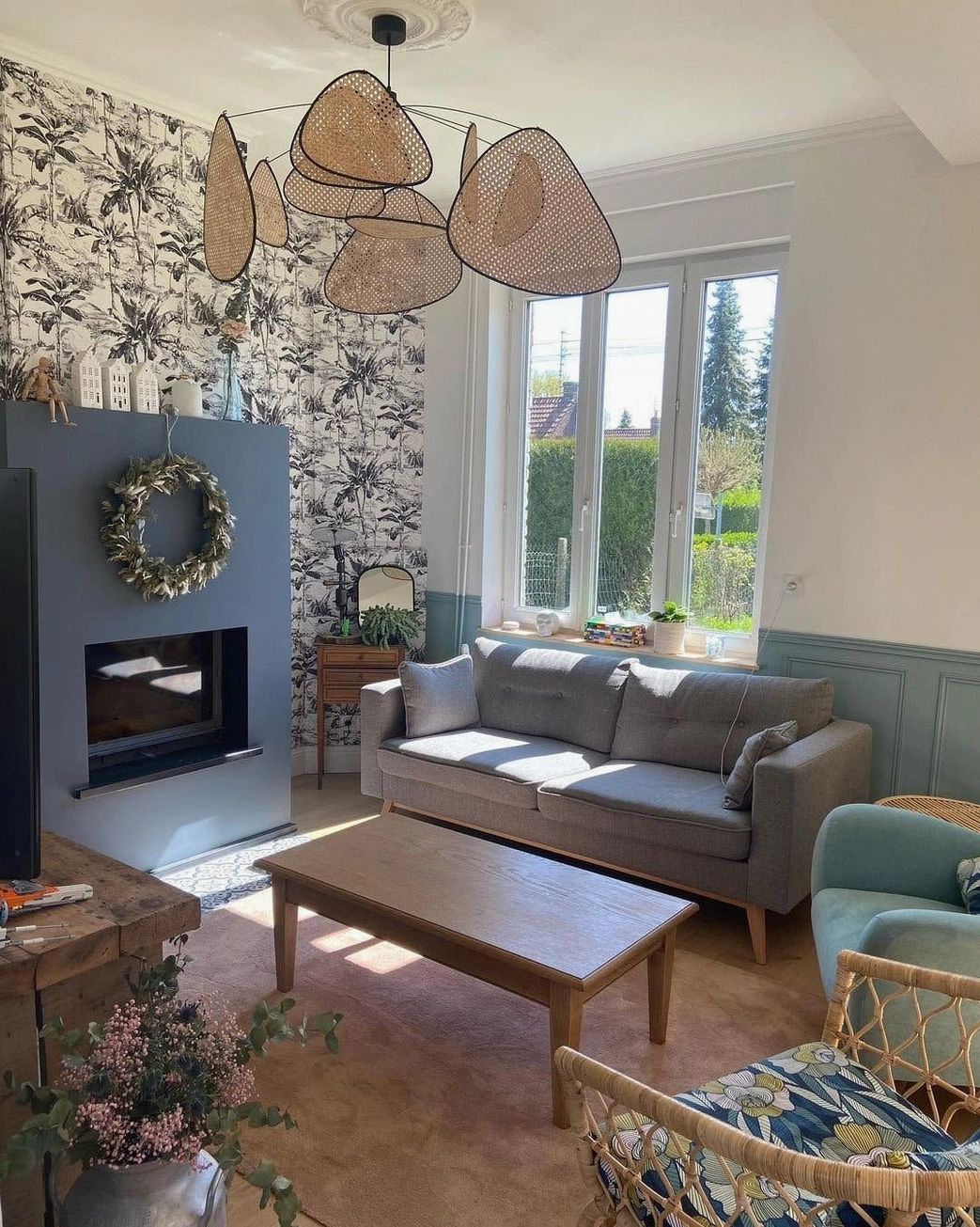 Rattan pendant chandelier in French country style home lounge, low-profile cluster design with floral wallpaper accent