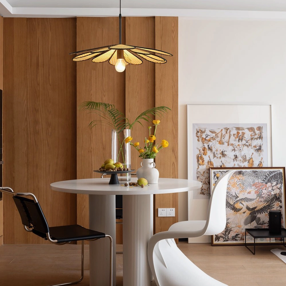 Sculptural rattan pendant lamp in minimalist dining nook with wood panel wall, potted plants and artistic decor