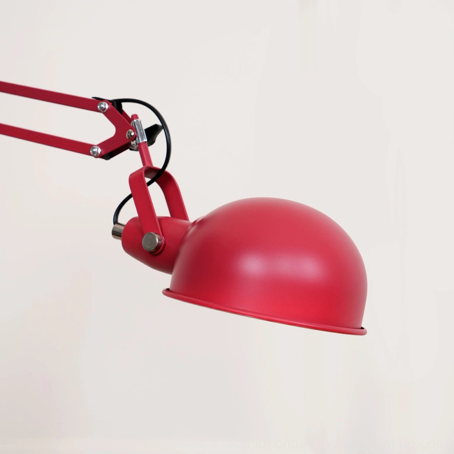 Red dome shade of adjustable floor lamp, close-up frontal view showing geometric metal construction and matte finish