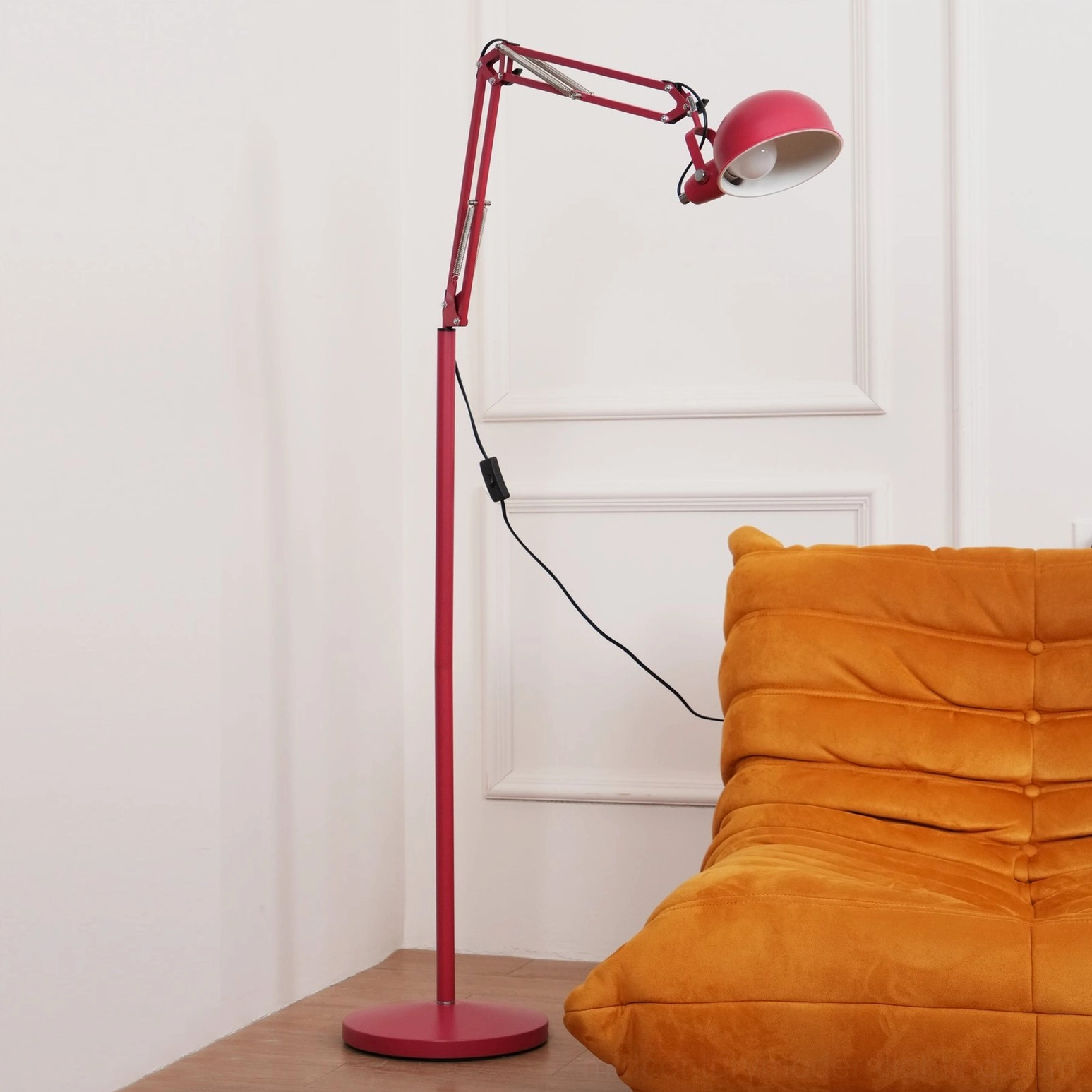 Red industrial floor lamp with extended swing arm in home interior, overhead perspective showing dome shade and black cord