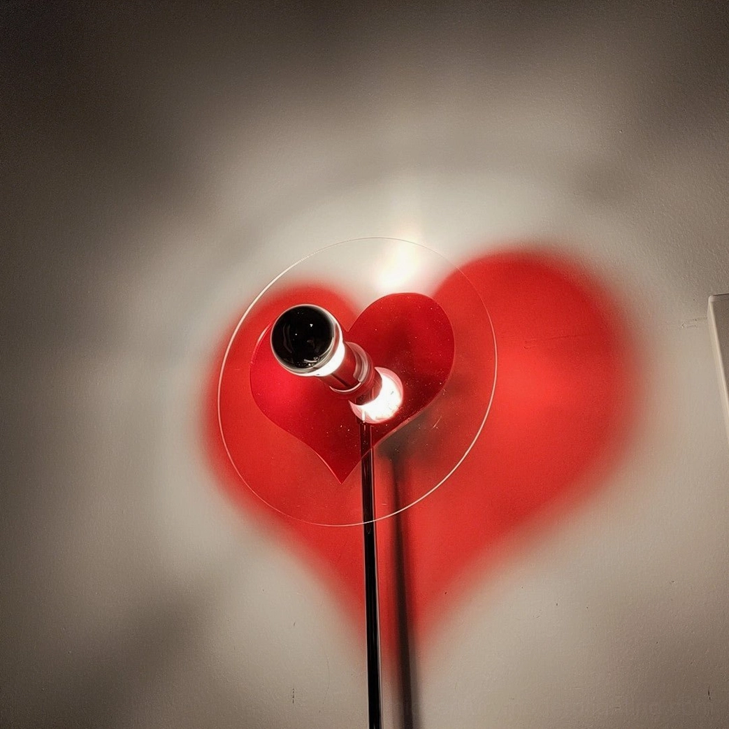 Red heart floor lamp with projection creating artistic shadow effect for modern home interior design