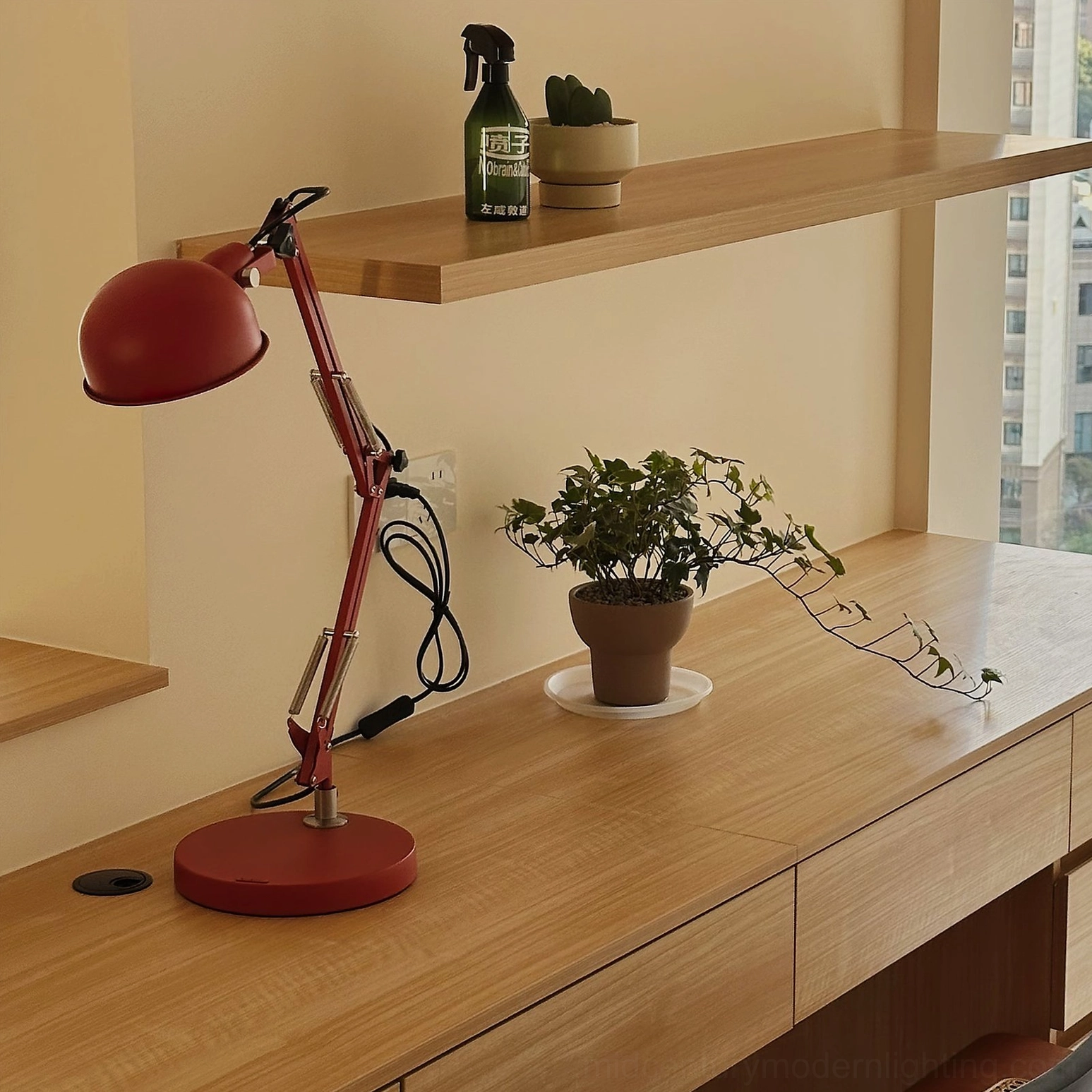 Red swing arm table lamp demonstrating full extension range and articulation for task lighting