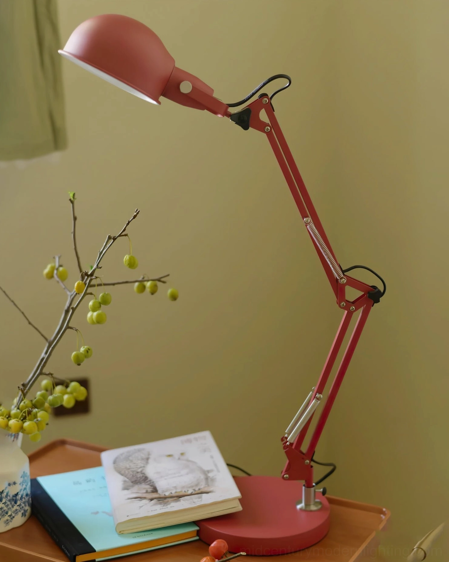 Red swing arm desk lamp paired with home office essentials demonstrating functional workspace design