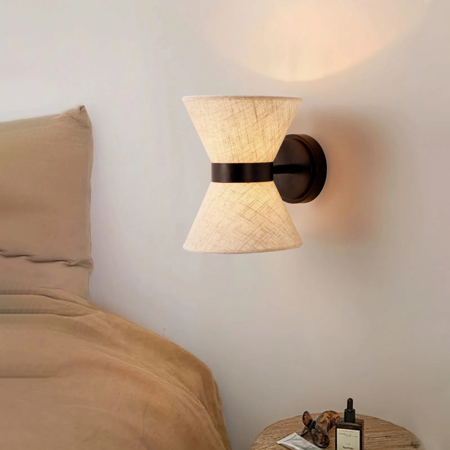 Renwick wall sconce installed above bedside in neutral bedroom with warm ambient lighting
