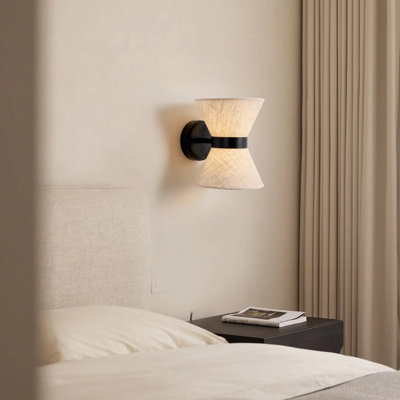Renwick wall sconce in modern minimalist bedroom with upholstered headboard and curtains