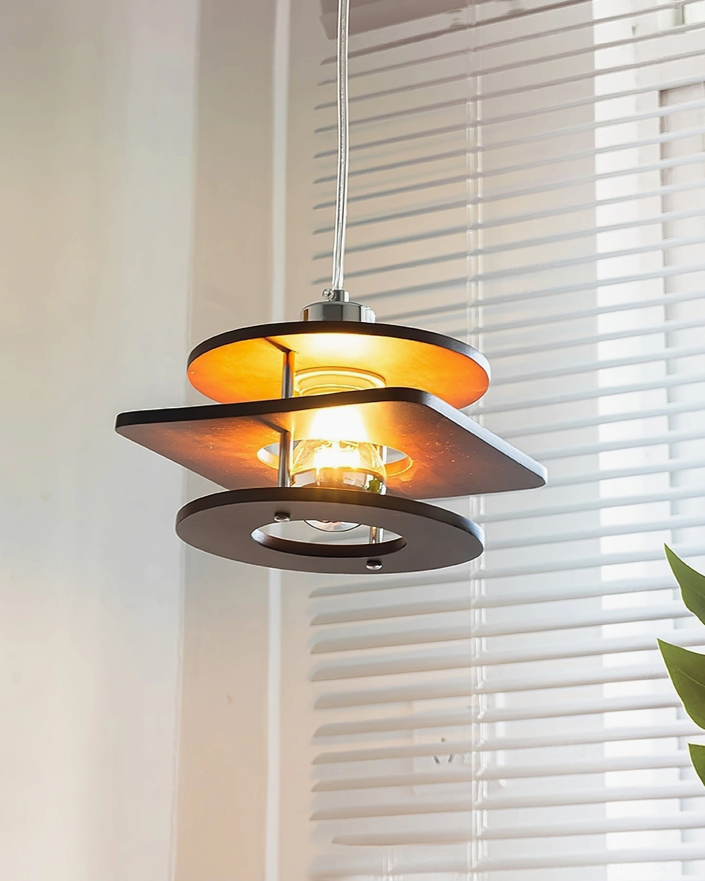 Retro walnut pendant lamp with amber inner shade, tiered wood construction and exposed Edison bulb, indoor setting