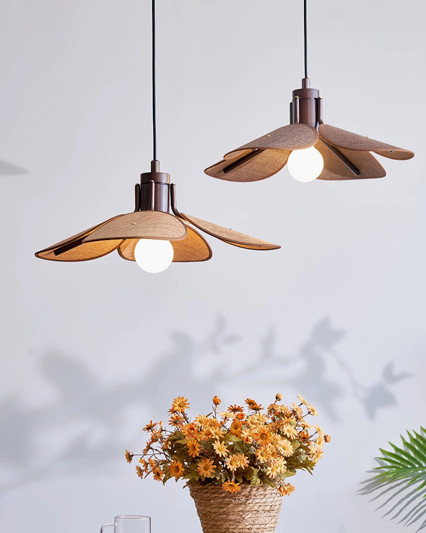 Dual Riankh woven pendant lights installed in corner with dried flower arrangement, low-angle view showing warm glow and exposed bulb design