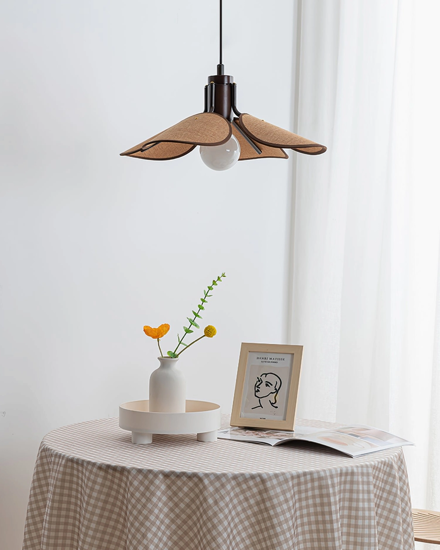 Single Riankh bohemian pendant lamp above cozy Nordic minimalist dining table with warm tabletop accessories