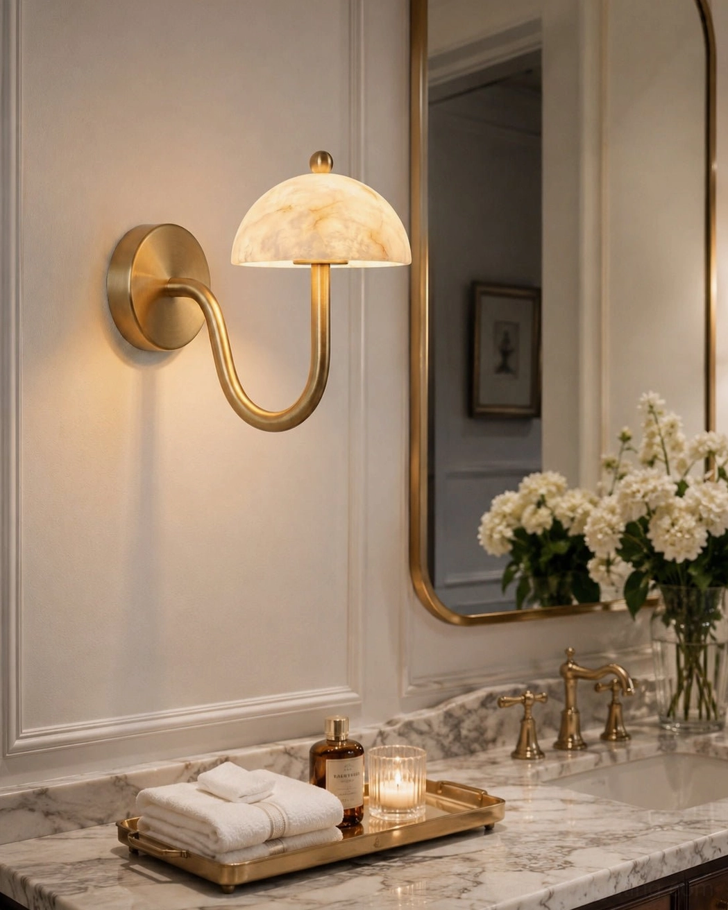 Ripple alabaster sconce flanking bathroom vanity mirror coordinated with brass fixtures
