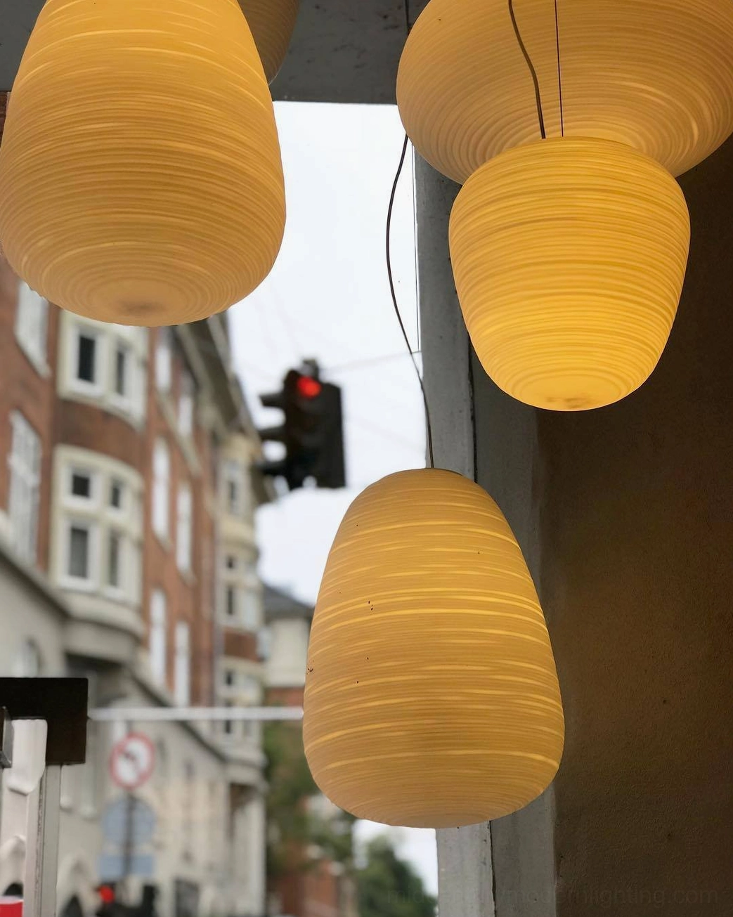 Rituals pendant light amber teardrop shape urban commercial building exterior warm glow