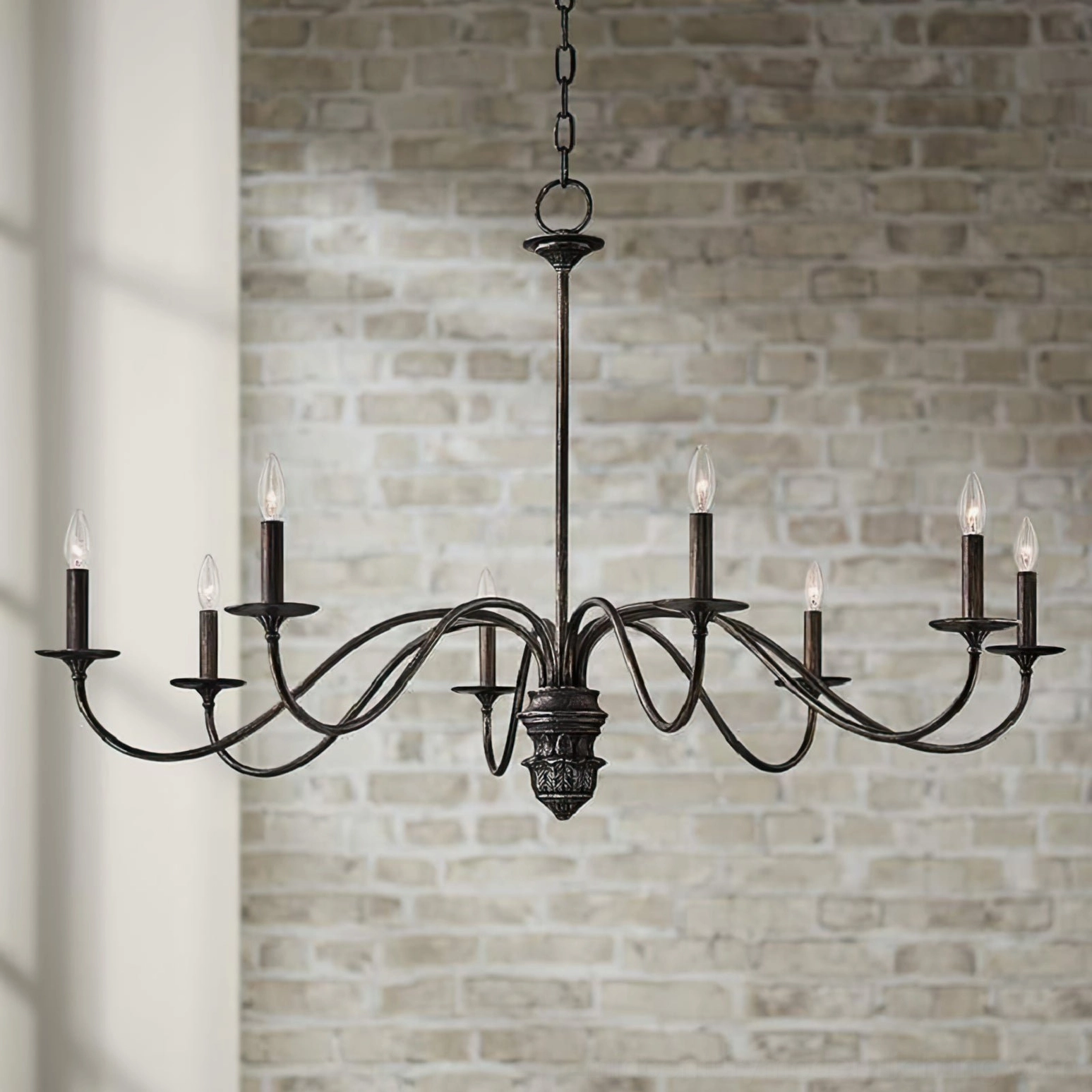 Rohan 8-light black rustic chandelier installed against brick wall in traditional farmhouse aesthetic side view