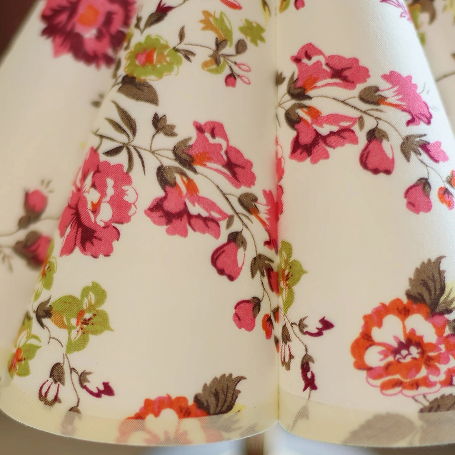 Detailed close-up of vivid red and pink rose prints on lamp shade with fine fabric texture