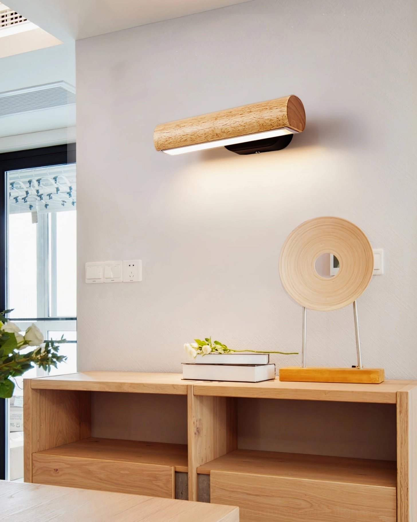 Wall-mounted rotatable lamp in minimalist home entryway with wooden shelf, cozy warm ambient lighting