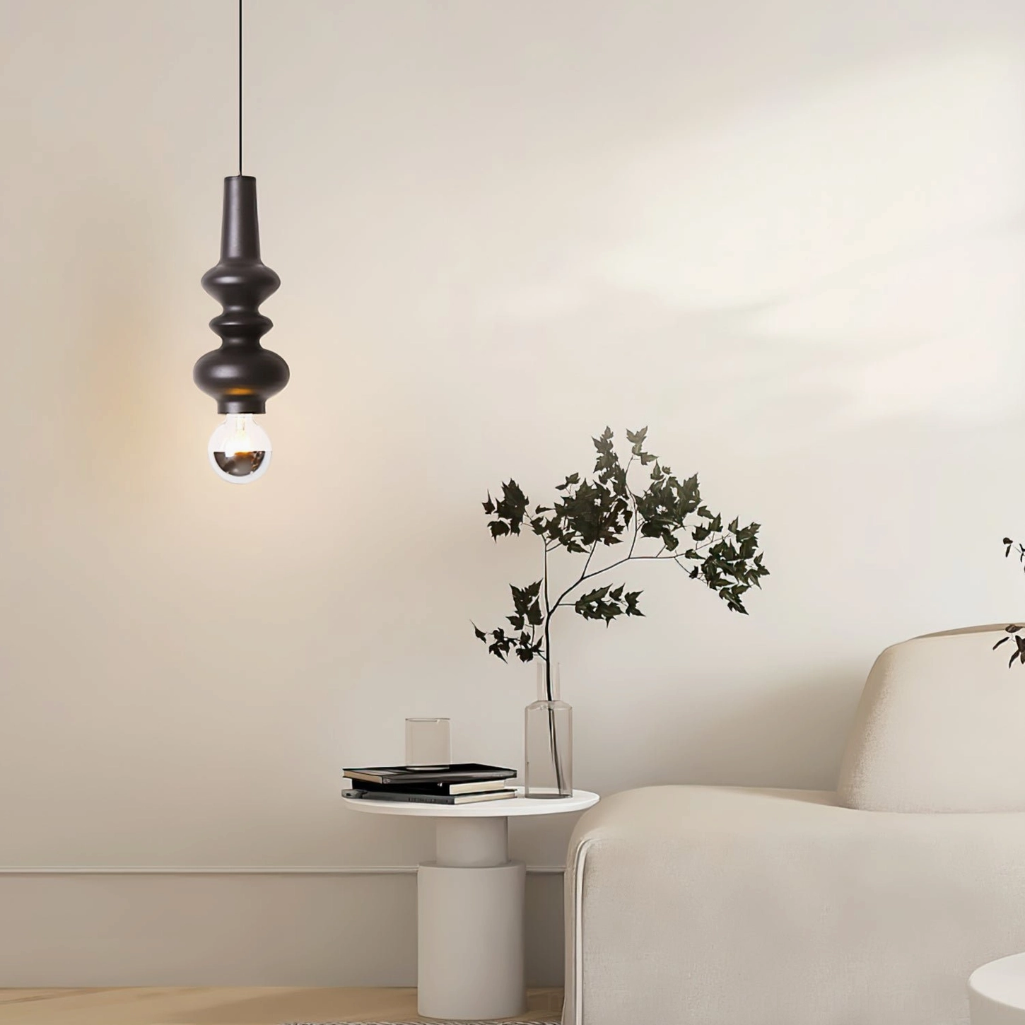 Rudd black cylindrical pendant hanging in minimalist living space with side table and green plant boho aesthetic