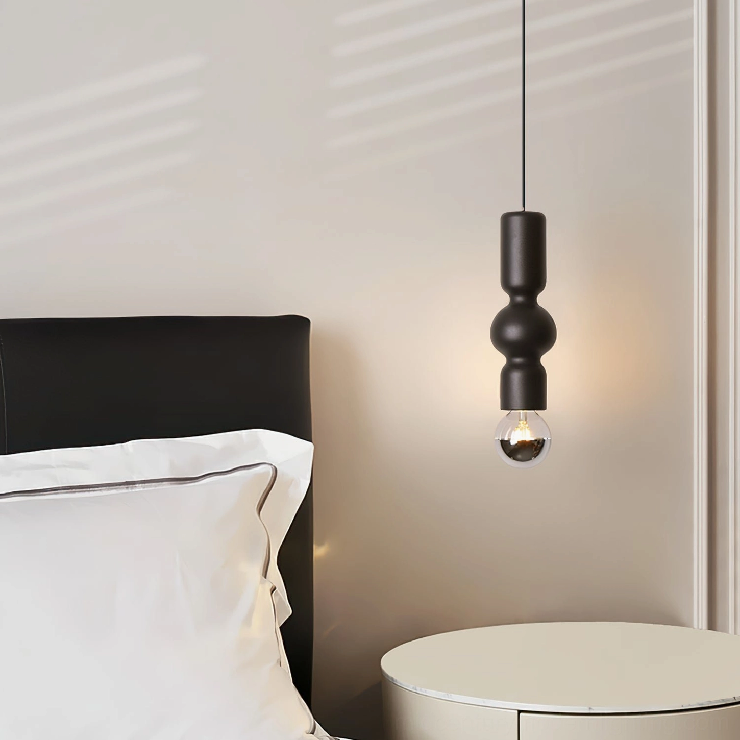 Rudd compact matte black pendant light hanging in minimalist bedroom with round side table