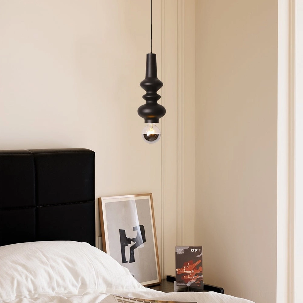 Rudd matte black cylindrical pendant light side view in mid-century modern bedroom with upholstered headboard