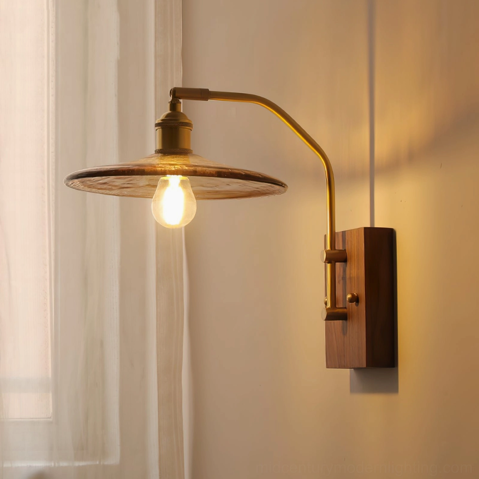 Side profile of Runia mid-century sconce with warm glowing bulb and dark walnut mounting plate, linen curtain background