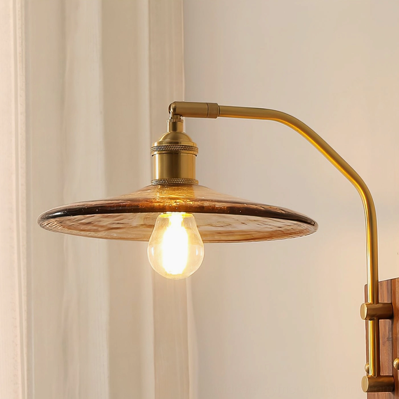 Runia farmhouse wall sconce with wide flared amber glass shade and curved brass arm, low-angle front view