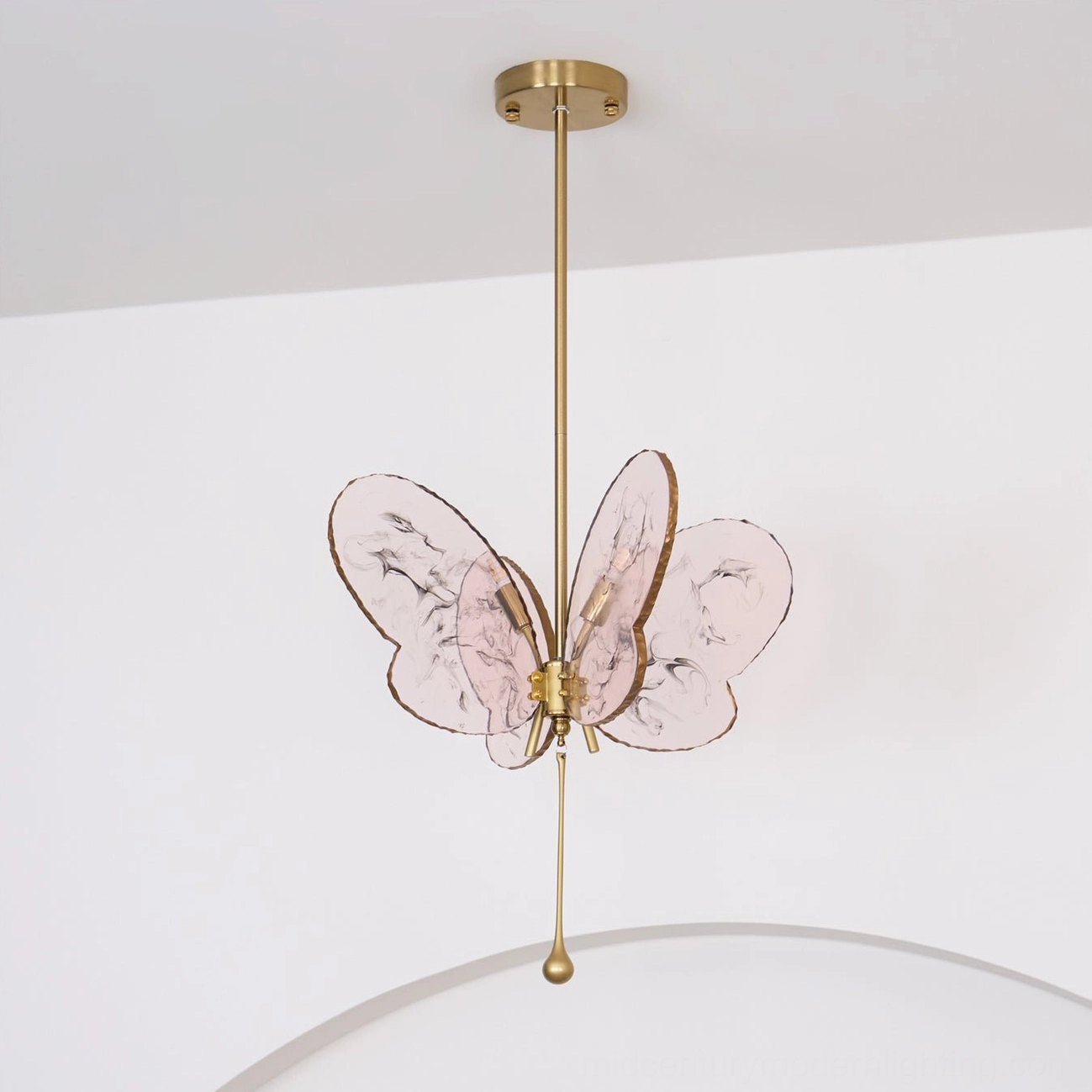 Overhead view of unlit pink butterfly pendant lamp with brass drop detail in decorated interior space