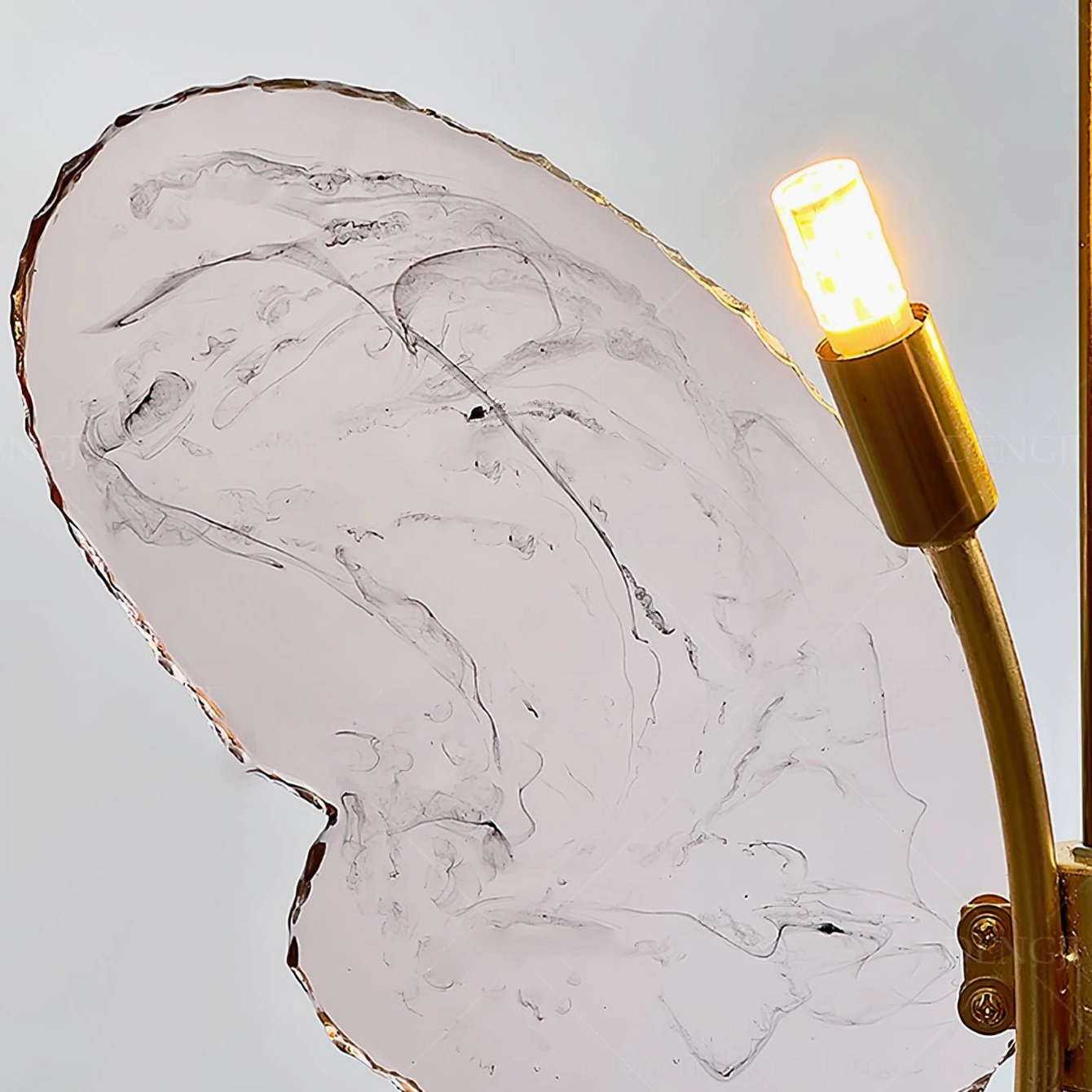 Close-up detail of pink butterfly pendant lamp showing hammered brass wing edges and bulb socket