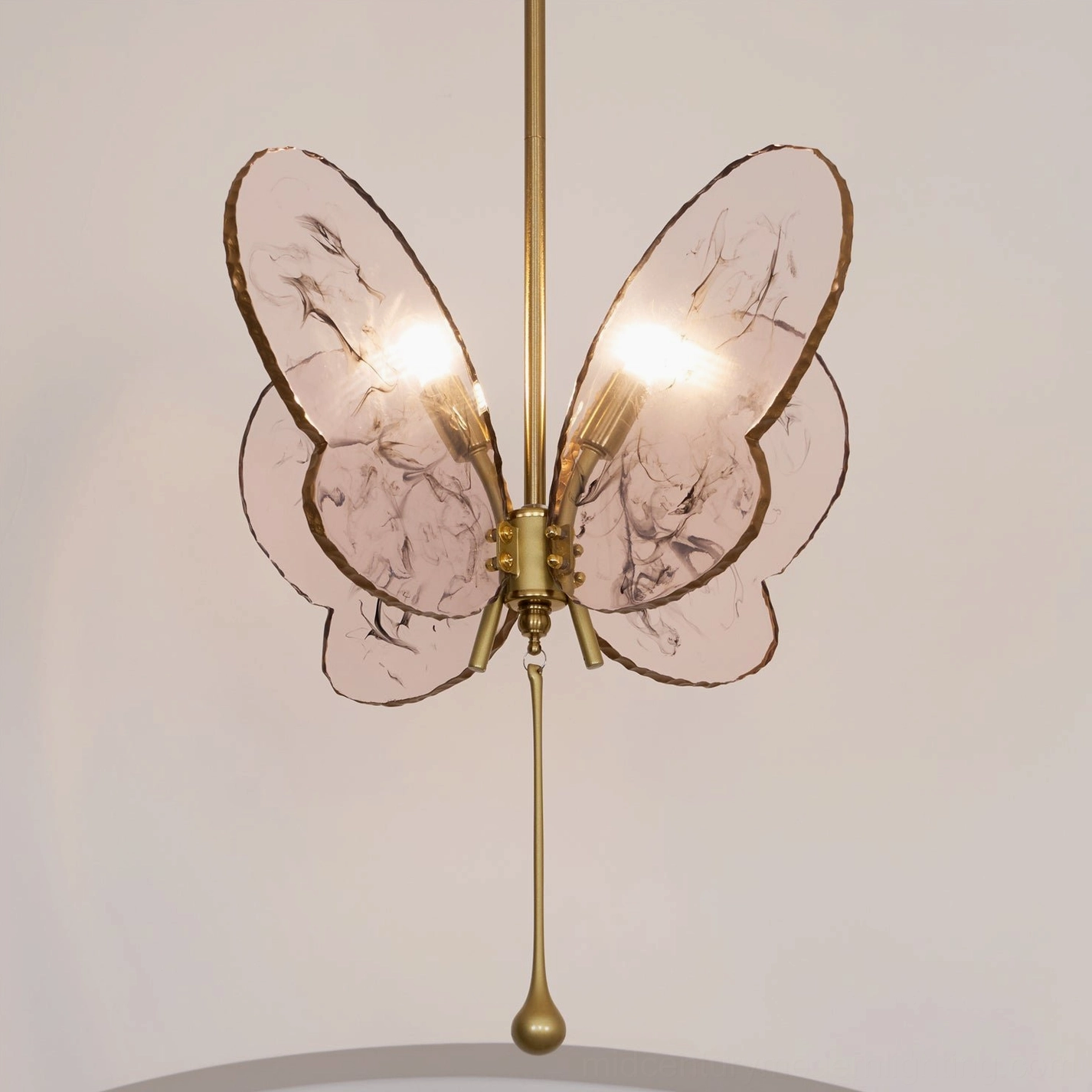 Lit pink butterfly pendant chandelier with warm glowing bulbs, brass gold hardware in studio backdrop