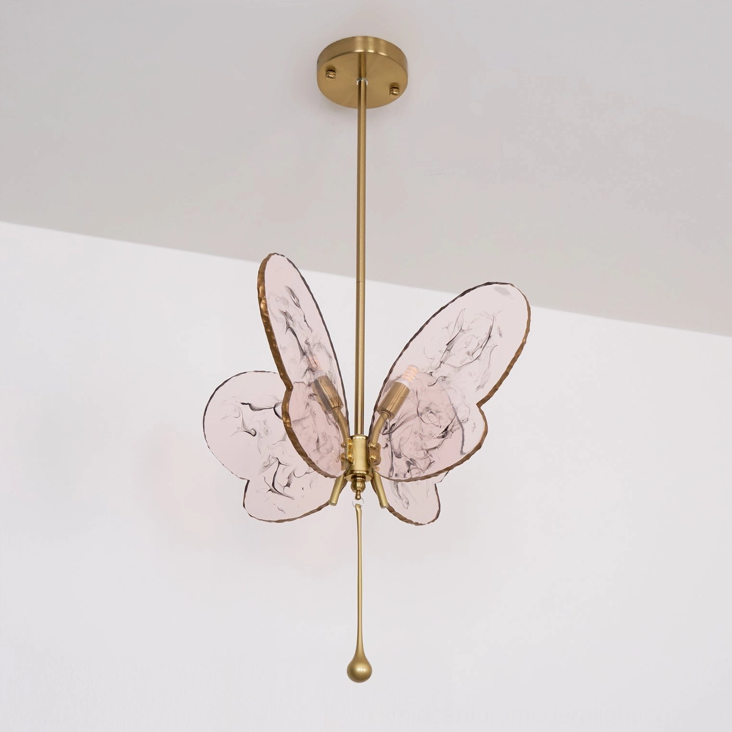 Side angle view of pink butterfly pendant lamp showing dimensional glass wing sculpture and brass frame