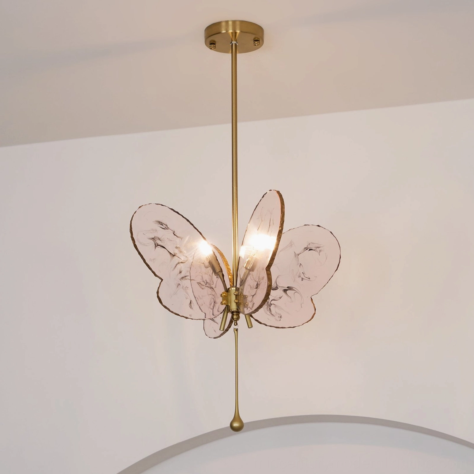 Pink butterfly pendant chandelier with brass drop accent in living room with curved ceiling design