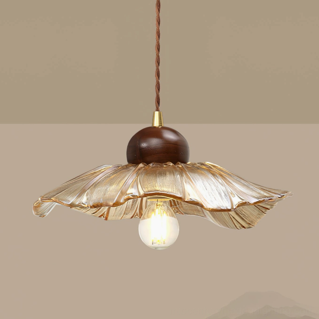 Close-up side view of scalloped amber glass pendant showing ruffled edges and twisted brown cord