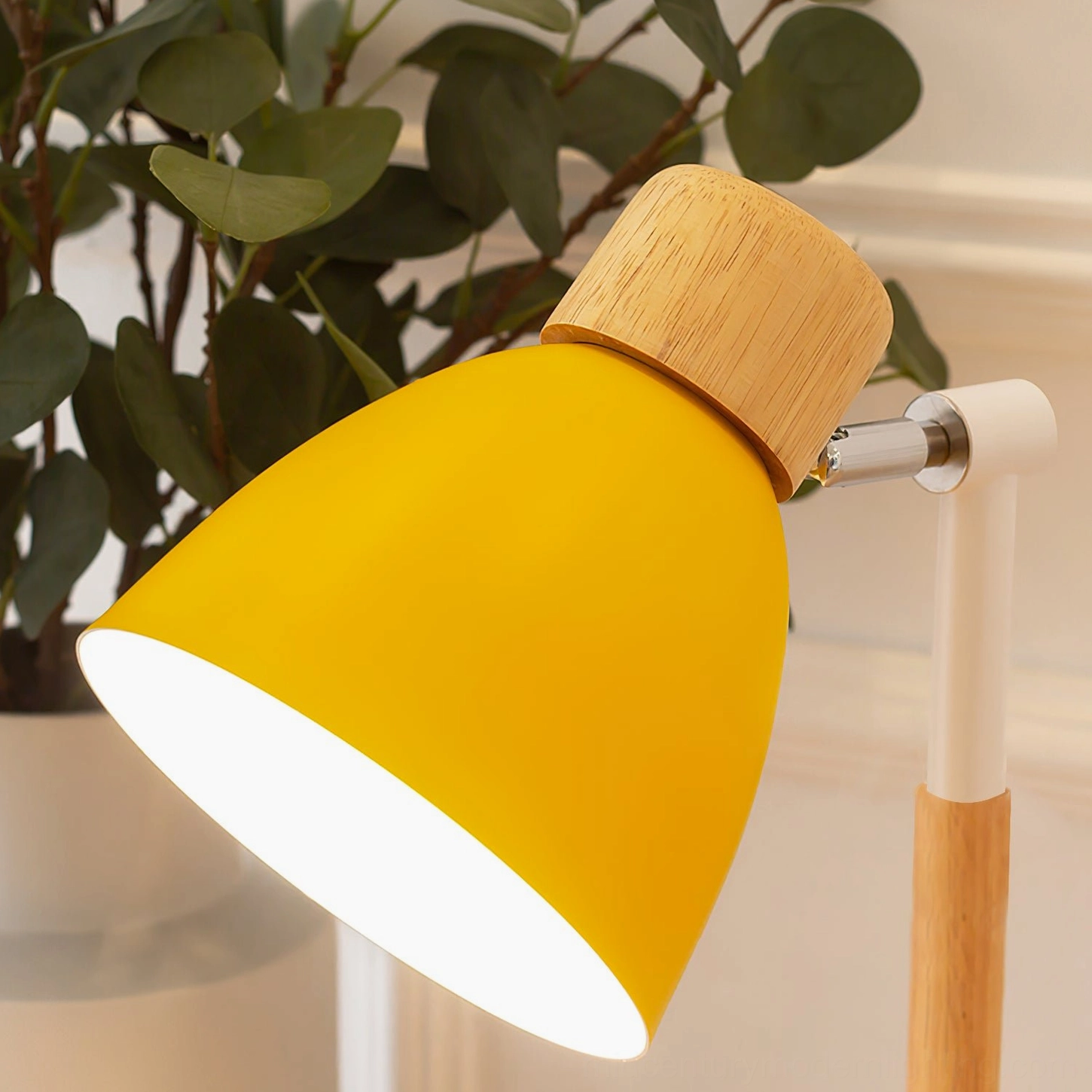 Close-up overhead view of yellow lamp shade head with solid wood cap and metal rotating joint detail